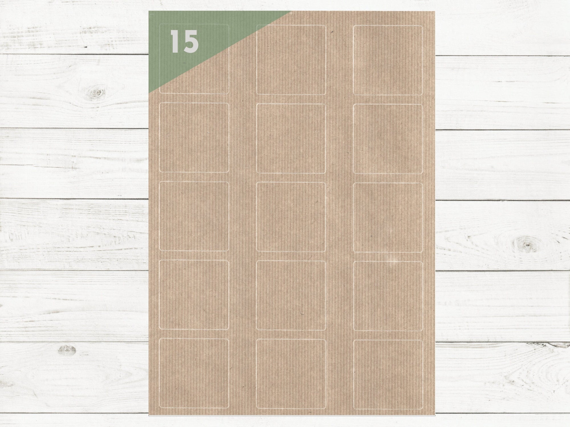 A4 Bogen mit 15 unbedruckten Kraftpapier Etiketten 50 x 50 mm auf weißem Holztisch. Es sind 15 bedruckbare Etiketten auf dem Bogen.